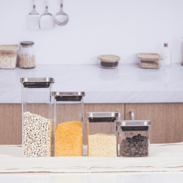 Square glass spice jars equipped with shiny stainless steel airtight lids, arranged neatly on a kitchen countertop