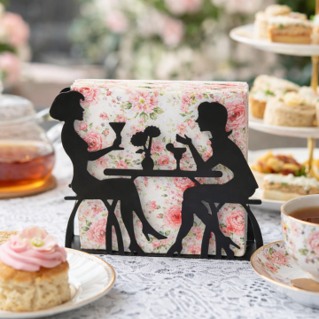 Metal napkin holder with silhouette couple design holding vintage floral napkins on a café table